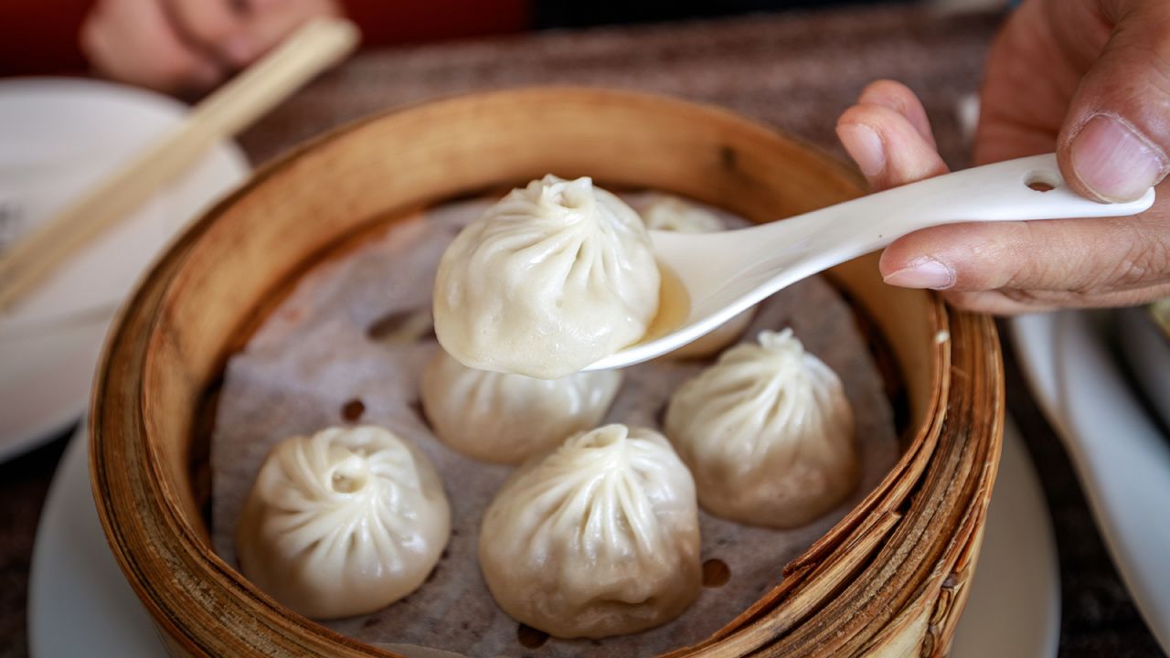 Use a spoon to catch the spilled soup from a xiaolongbao.