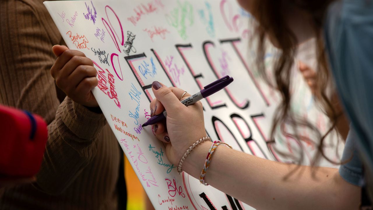 People sign a poster that reads 
